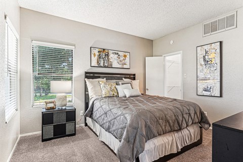 Comfortable bedroom with a grey upholstered bed and neutral decor at Laurels of Sendera apartments in Arlington, TX